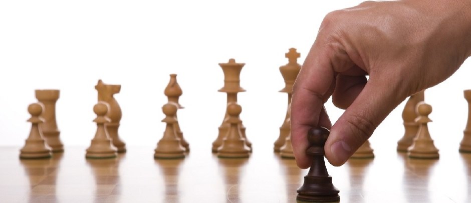 Schachfiguren auf einem Brett, eine Hand setzt einen Zug